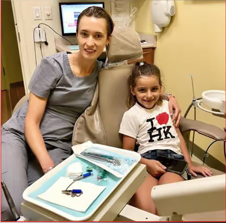 Child sitting beside a dental hygienist during a dental appointment.